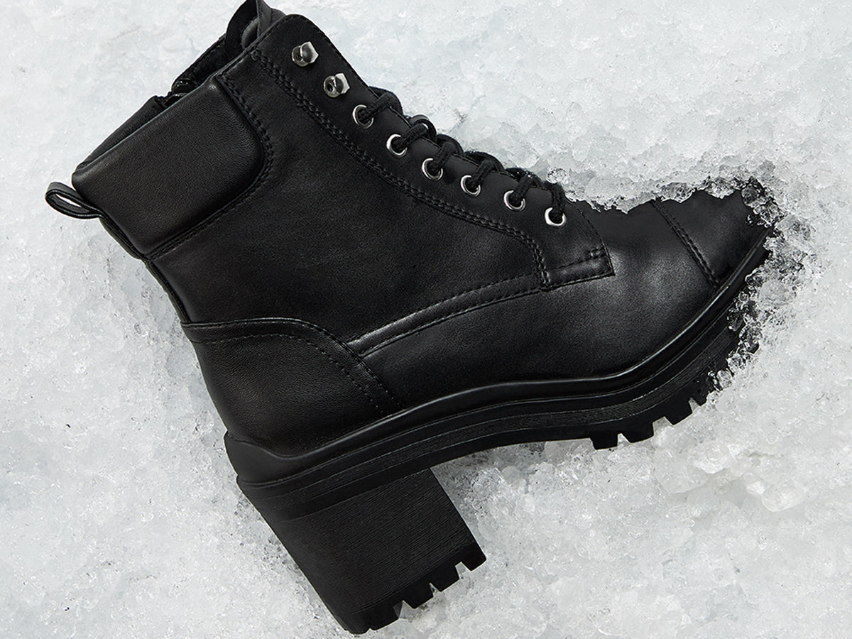 Black leather boot on a snowy ground.