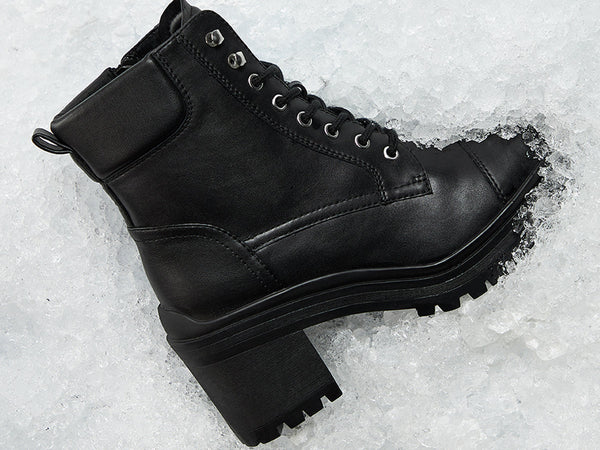 Black leather boot on a snowy ground.